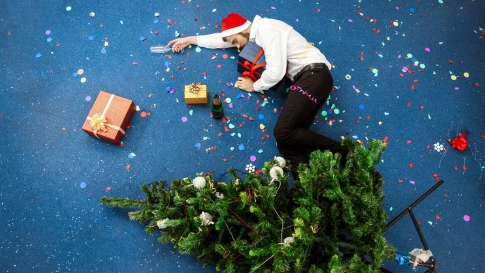 Symbolbild: Weihnachtsfeier, Betrunkener Mann liegt vor Weihnachtsbaum